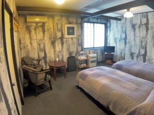 Un dormitorio con dos camas y un escritorio y una silla. en Rickshaw inn, en Takayama