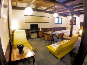 una camera con un letto e un tavolo con un divano giallo di Rickshaw inn a Takayama