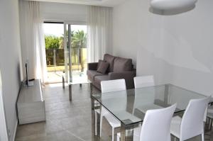 a living room with a glass table and white chairs at Green 12, 1 dormitorio, Oliva Nova, by Bookindenia in Oliva