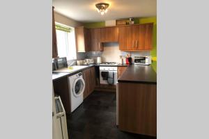 cocina con armarios de madera, lavadora y secadora en Dudley House **Staycation & Contractors** Sleeps 7, en Tipton