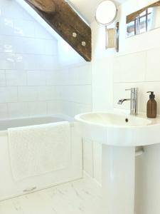 uma casa de banho branca com um lavatório e uma banheira em The Attic Apartment, Quay Street Studios Cardigan em Cardigan