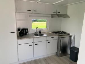 a kitchen with white cabinets and a sink and a window at Chalet S1 in Workum bij strand en IJsselmeer in Workum