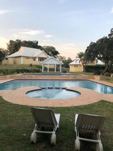 two chairs sitting in front of a swimming pool at Caribbeans Estates Villa T13 Tortuga in Port Edward