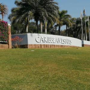 a sign for a park with palm trees in the background at Caribbeans Estates Villa T13 Tortuga in Port Edward
