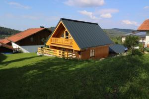 a wooden house with a balcony on a green field at Chalet Fuchsberg in Mauth