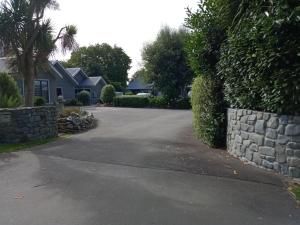 a driveway with a stone wall and a house at Four Peaks Motel in Geraldine