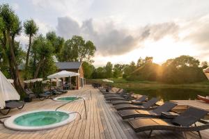 a deck with chairs and a hot tub next to a lake at Hotel Azzun Orient SPA&Wellness in Kromerowo