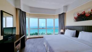 a hotel room with a bed and a large window at Ramada by Wyndham Beach Hotel Ajman in Ajman 