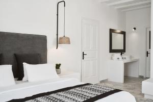 a white bedroom with a bed and a mirror at Mr & Mrs White Mykonos in Platis Gialos