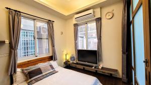 台東市的住宿－悅夜民宿，一间卧室设有一张床、一台电视和两个窗户。