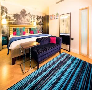 una camera con letto, divano e tavolo di Hotel Indigo London Hyde Park Paddington, an IHG Hotel a Londra