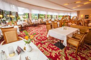 un restaurante con mesas y sillas blancas y alfombra roja en Hotel Hahnenkleer Hof, en Hahnenklee-Bockswiese