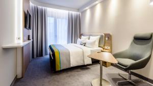 um quarto de hotel com uma cama e uma cadeira em Holiday Inn Express - Rosenheim, an IHG Hotel em Rosenheim