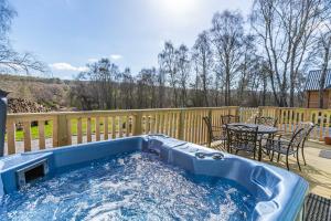 a hot tub on a deck with a table and chairs at Heather Lodge 17 with Hot Tub in Belladrum