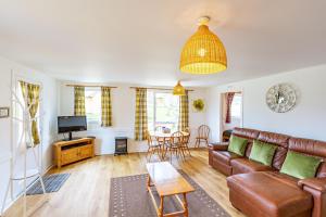 a living room with a couch and a table at Heather Lodge 17 with Hot Tub in Belladrum