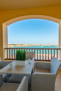 a balcony with wicker chairs and a table with a plant at Golden Apartments El Gouna in Hurghada