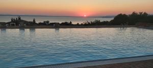 a large swimming pool with a sunset in the background at Casale sul Lago Trasimeno in San Feliciano