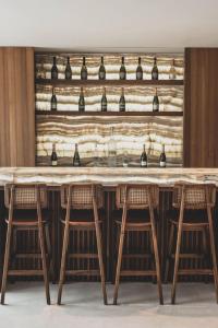 a bar with three stools in front of a wall of wine bottles at OKU Ibiza in San Antonio