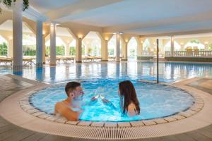a man and a woman in a swimming pool at Möhringers Schwarzwald Hotel in Bonndorf im Schwarzwald