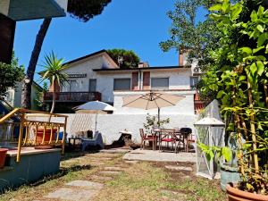 eine Terrasse mit einem Tisch, Stühlen und einem Sonnenschirm in der Unterkunft Villa Versilia in Lido di Camaiore