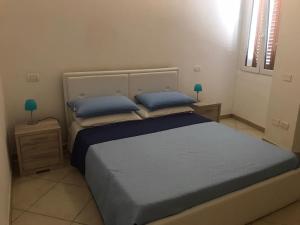 sypialnia z łóżkiem z niebieską pościelą i niebieskimi poduszkami w obiekcie Casa Francesca w mieście Carloforte