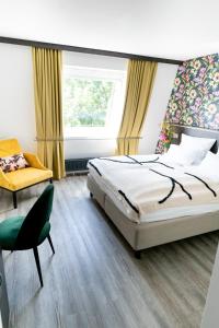 um quarto com uma cama, uma cadeira e uma janela em Luxstay Karben - Self-Check-In em Karben
