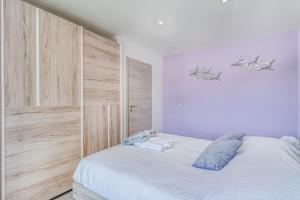 ein Schlafzimmer mit einem weißen Bett und einer Holzwand in der Unterkunft Les Roseaux in Sanchey