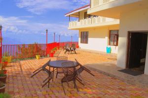 a patio with a table and chairs and a building at Hotel Himdhara, Dalhousie in Dalhousie