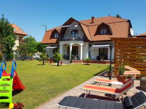 Casa con patio con sillas y parque infantil en Gabi Apartmanház en Balatonlelle