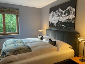 1 dormitorio con 1 cama, 2 lámparas y una pintura en Kitzbühel Beach Chalet " Ski-in & Ski-out ", en Kitzbühel