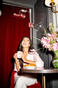 a woman sitting at a table with a cup of coffee at Luxstay Karben - Self-Check-In in Karben