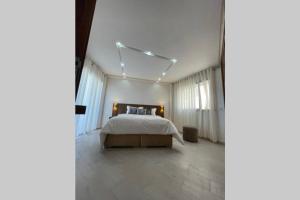 a bedroom with a large bed with white sheets and curtains at Superbe appartement en front de mer haut standing in Kenitra