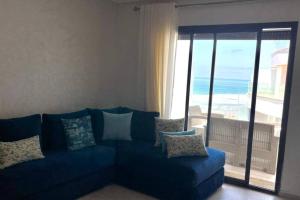 a blue couch in a living room with a view of the ocean at Superbe appartement en front de mer haut standing in Kenitra