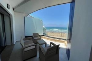 a room with chairs and a view of the beach at Superbe appartement en front de mer haut standing in Kenitra