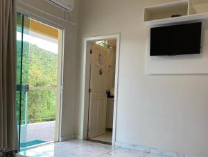 um quarto com uma televisão de ecrã plano na parede em Pousada Nascer do Sol em Penha