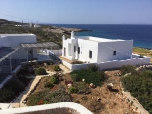 une maison blanche avec un jardin à côté de l'océan dans l'établissement Makares, à Donoussa