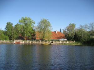 una casa a orillas de un lago con un barco en Viesu nams Vella Dzirnavas, en Dzirnavas