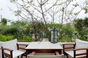 uma mesa de madeira com cadeiras brancas e uma árvore em Marili Apartments Studios em Parasporos