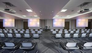 a conference room with chairs and screens in it at Hotel La Tour in Milton Keynes