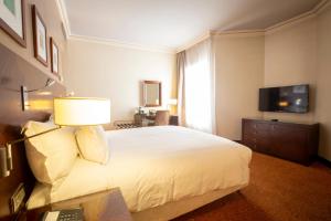 sypialnia z dużym białym łóżkiem i telewizorem w obiekcie Hotel Atlantic Agdal w mieście Rabat
