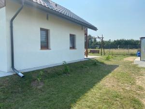einen seitlichen Blick auf ein weißes Haus mit einem Hof in der Unterkunft Domek na Mazurach RoJo, Polska Wieś 26H in Mrągowo