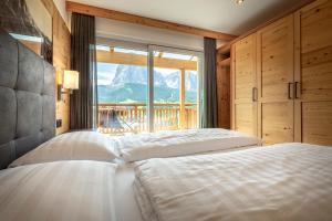 a bedroom with two beds and a large window at Apartments La Mana in Santa Cristina in Val Gardena