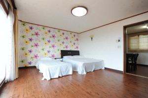 two beds in a room with flowers on the wall at Jeju Feel House in Jeju
