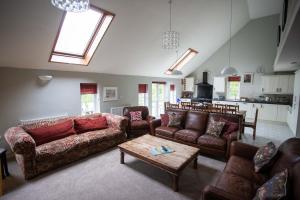 a living room with couches and a table at Wellstone Cottages - Honey Coach House in Pembrokeshire
