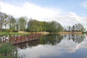 un puente sobre un lago con reflejos en el agua en Danielówka, en Pępowo