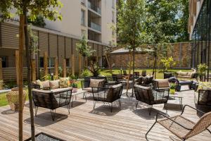 un patio con sedie e tavoli su una terrazza in legno di Residhome Toulouse Ponts Jumeaux a Tolosa