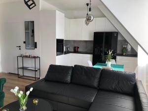 a living room with a black couch and a kitchen at Apartament Zielone Fotele Starówka in Olsztyn
