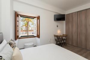 1 dormitorio con cama, ventana y escritorio en Taah Billa Guest House, en Tavira