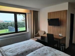 a hotel room with a bed and a desk and a window at Landgasthaus Berns De Bakker in Engden