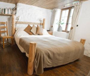 een slaapkamer met een houten bed met kussens en een stoel bij Beautiful renovated chalet near ski resort France in Arâches-la-Frasse